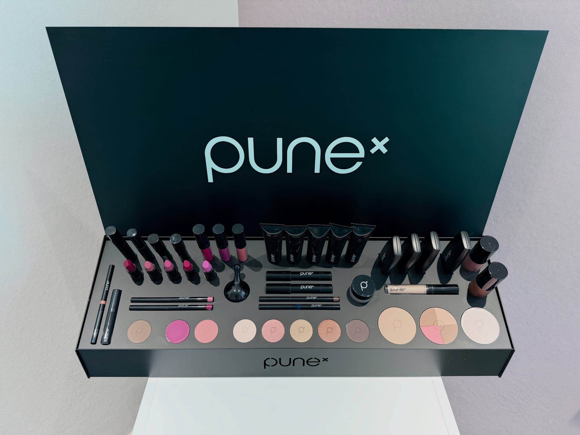 Geöffneter PUNE-Make-up-Koffer mit Pinseln, Lippenstiften und Lidschattenfarben im Hautatelier Kastlan.