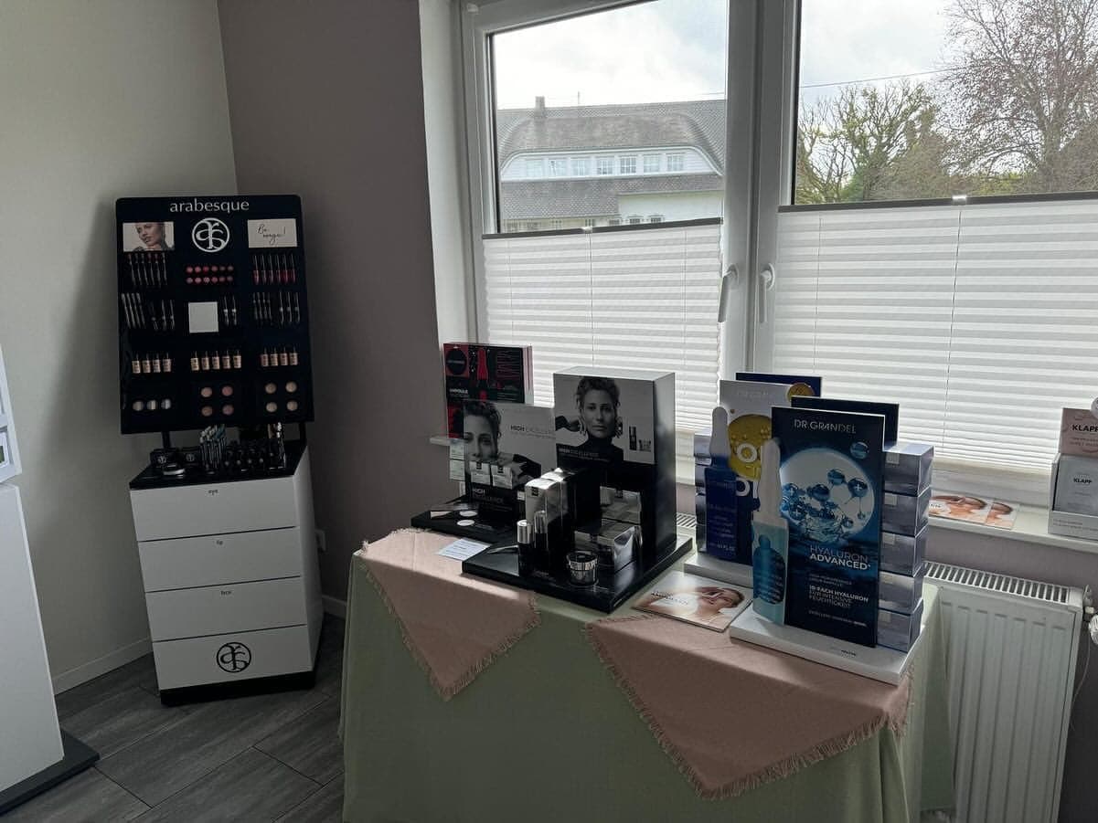 Make-up-Station am Fenster des Instituts: Farbständer neben einem Präsentationstisch mit Pflegeprodukten im Tageslicht.