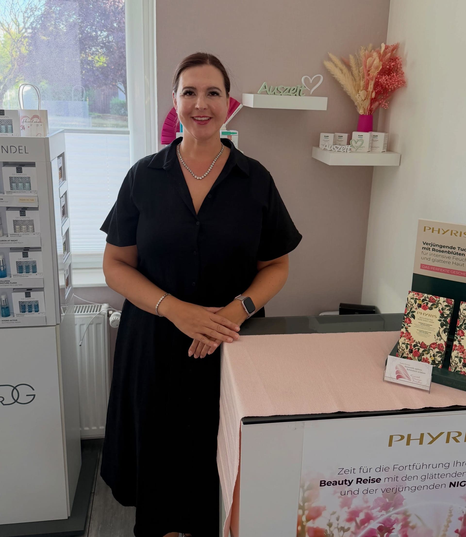 Saskia Kremer-Kastlan, Inhaberin des Hautatelier Kastlan in Merzig-Menningen, steht im Tageslicht neben einem PHYRIS-Display in ihrem Institut.