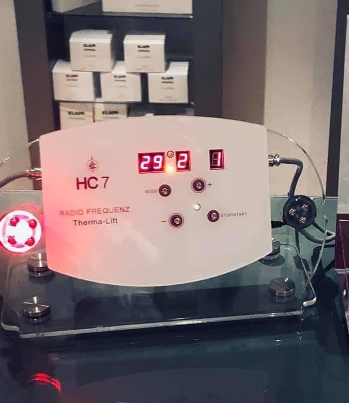 Das HC7 Radiofrequenz-Gerät für Thermo-Lift-Anwendungen mit beleuchteter Anzeige, daneben ein Ständer mit Wirkstoffampullen.